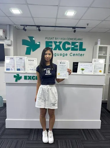 A student holding her certificate at Excel Language Center